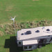Aerial view of a recreational vehicle with a wind turbine on a grassy field
