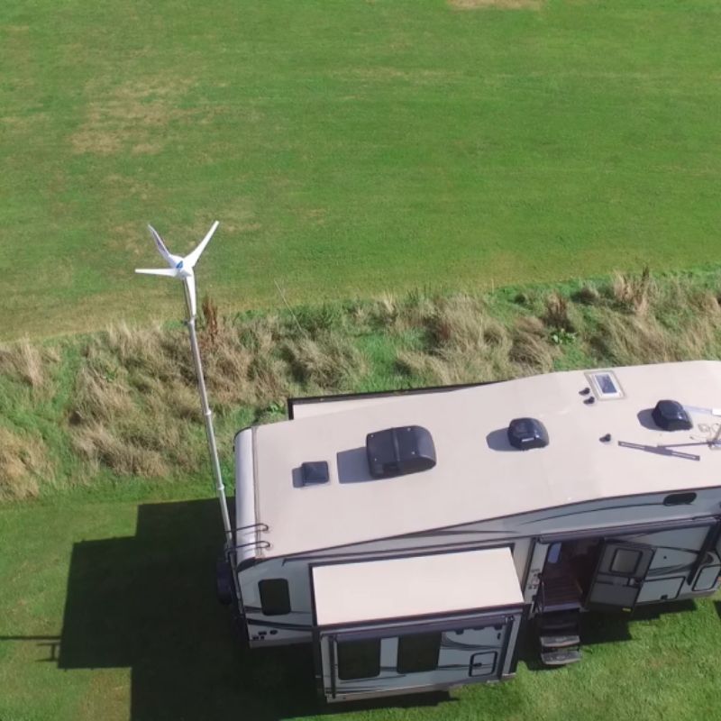 Aerial view of a recreational vehicle with a wind turbine on a grassy field